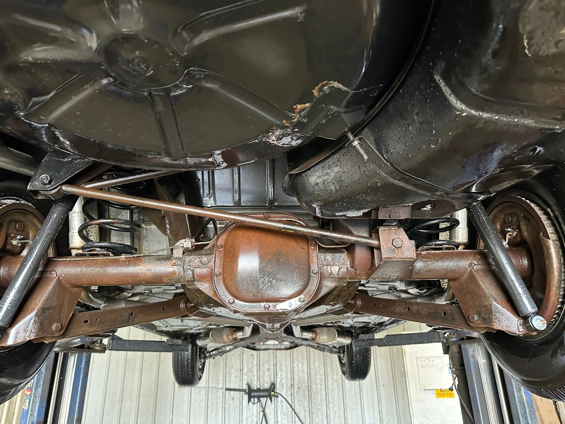 1966 Buick Riviera Versus 1966 Oldsmobile Toronado – Closely Related, Yet So Different (Part 1) 24 Rear axle and suspension of a Silver Green 1966 Buick Riviera, seen from below and behind with the car on a hoist