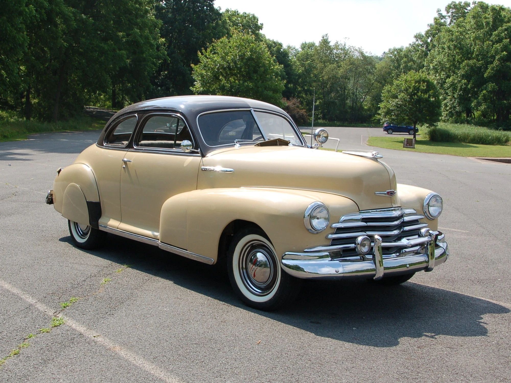 Front 3q view of a brown and beige 1947 Chevrolet Fleetmaster sport coupe in a parking lot in the sun