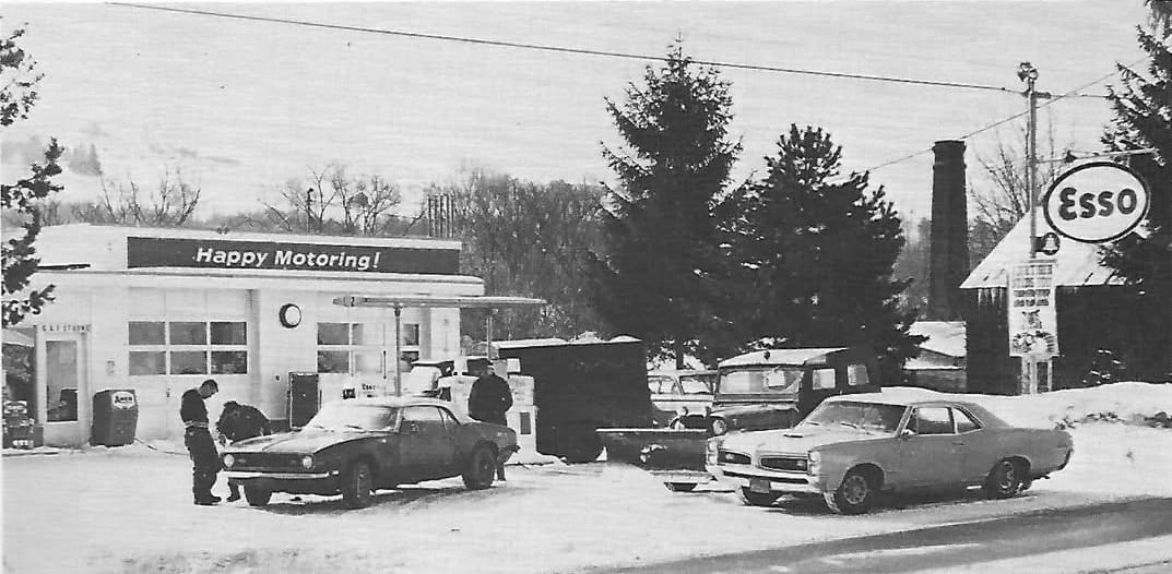 What Cars And Trucks Did Americans Buy In 1969? – A CC Auto Yearbook Feature 33 B&W photo of a snow-covered Esso station with a 1966 Pontiac GTO coupe and a 1967 Chevrolet Camaro convertible in front