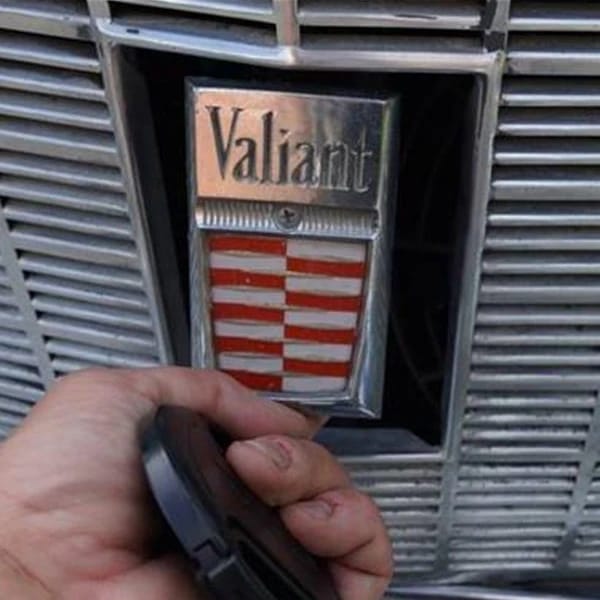Vintage R&T Review: 1960 Valiant — A Technical Analysis Of Chrysler's New Compact 25 Closeup of the Valiant badge on the grille of a 1960 valiant, with the photographer's left hand holding a black plastic object