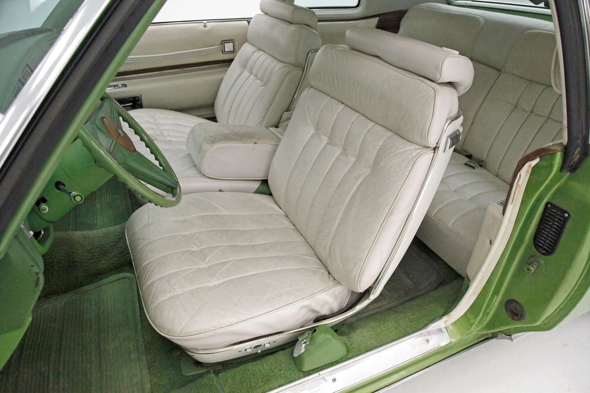 Front seat of a Persian Lime Firemist 1974 Cadillac Coupe de Ville with white leather
