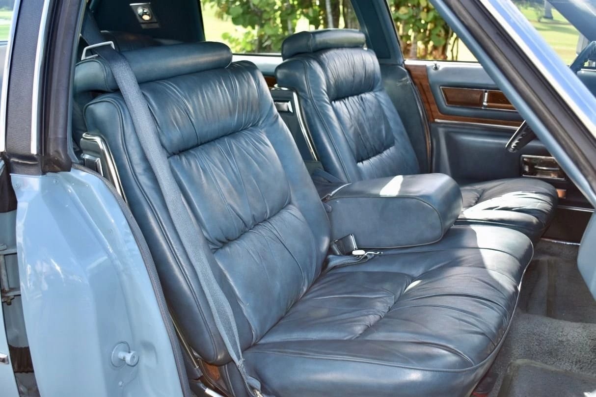 Front seat of a 1975 Cadillac Fleetwood Brougham with blue leather, viewed through the right front door