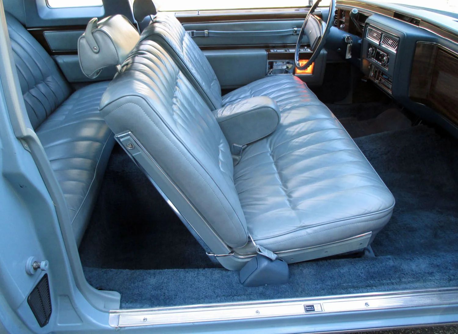 Front seat of a 1977 Cadillac Coupe de Ville with light blue leather, viewed through the passenger door