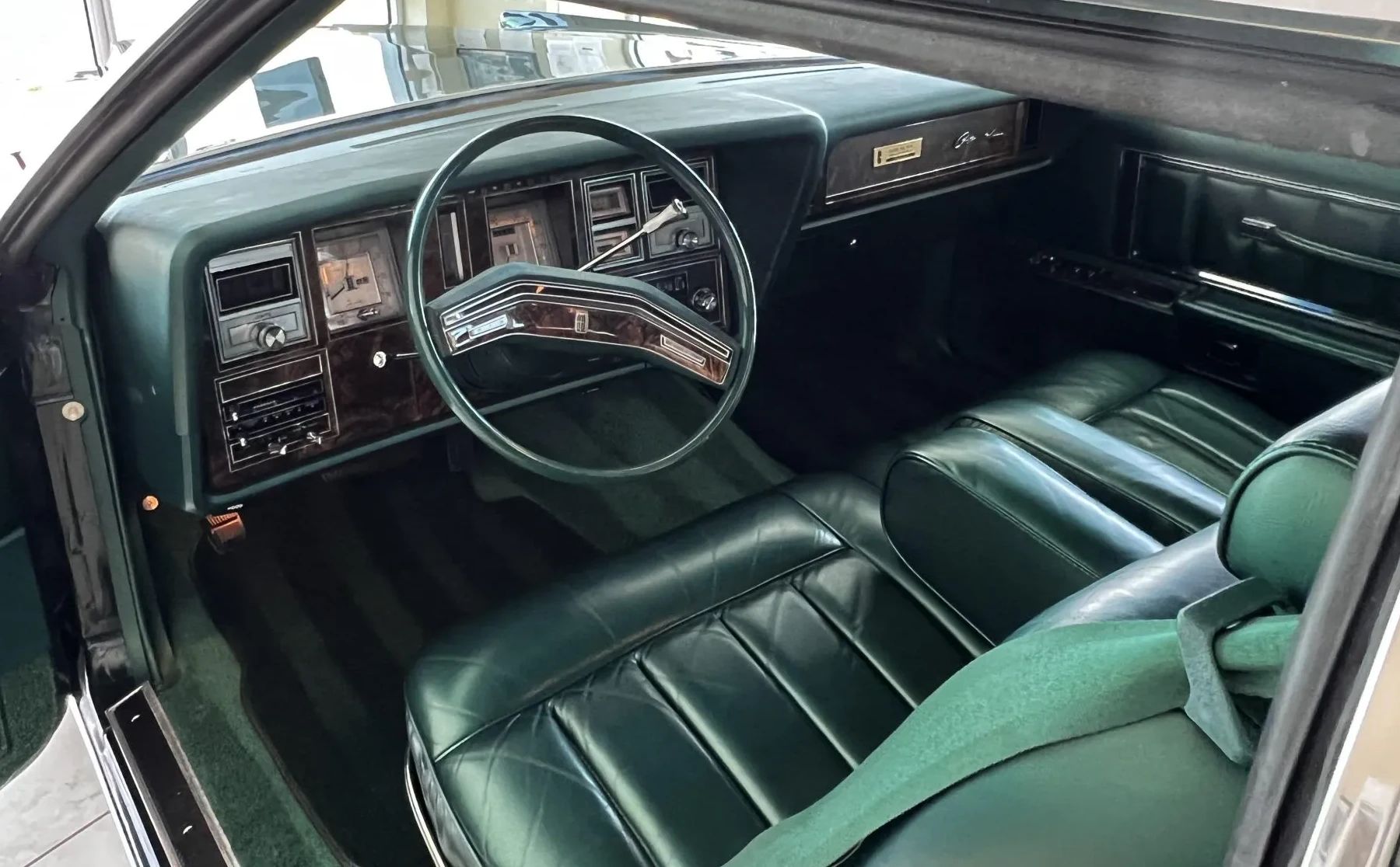 Dashboard and front seat of a 1978 Lincoln Continental Mark V Givenchy Edition with green leather, seen through the driver's door