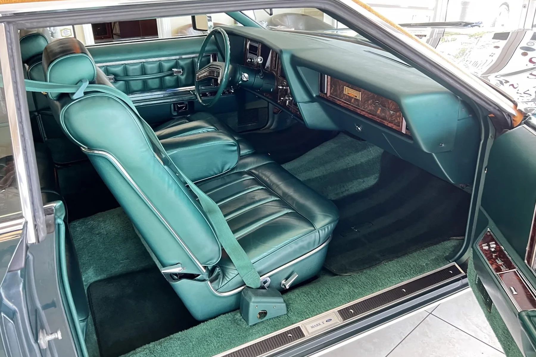 Front seat and dashboard of a 1978 Lincoln Continental Mark V Givenchy Edition with green leather, viewed through the passenger door