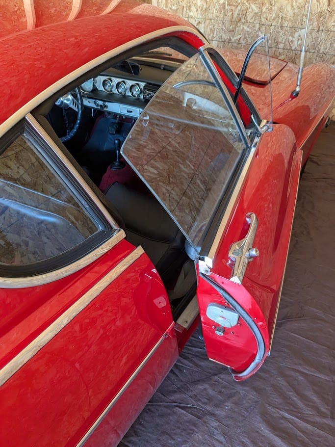 The Volvo 1800S in the garage with the passenger door open