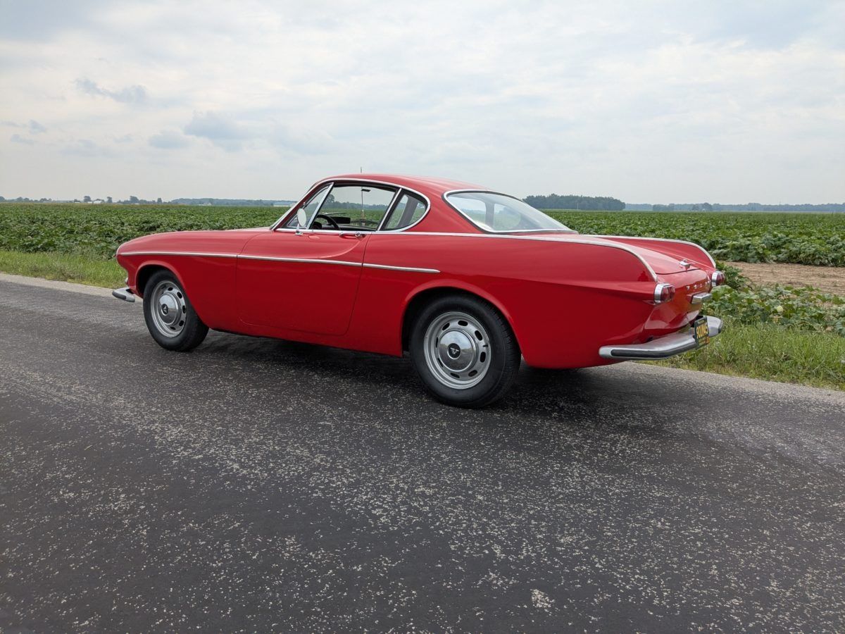 Another photo of the red 1967 Volvo 1800S on a country road