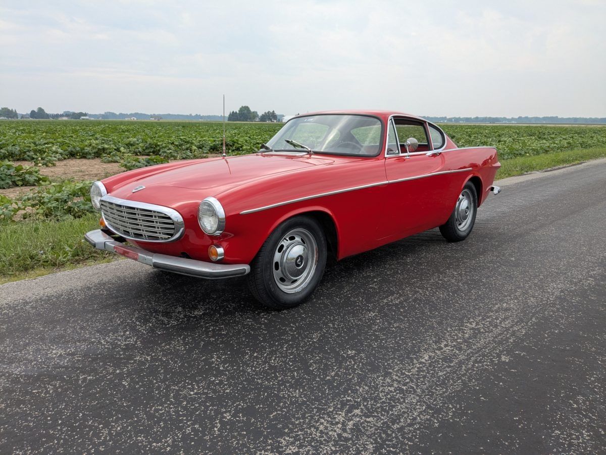 Photo of a red 1967 Volvo 1800 S coupe parked on a country road
