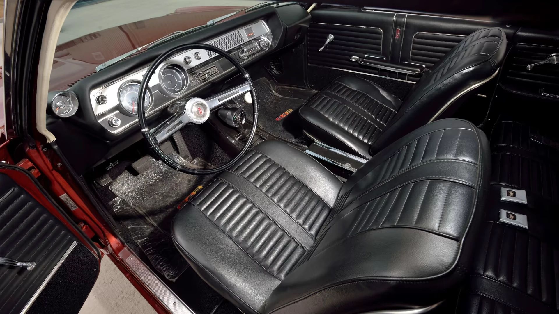 Front seats of a bronze 1966 Oldsmobile 4-4-2 hardtop viewed through the driver's door