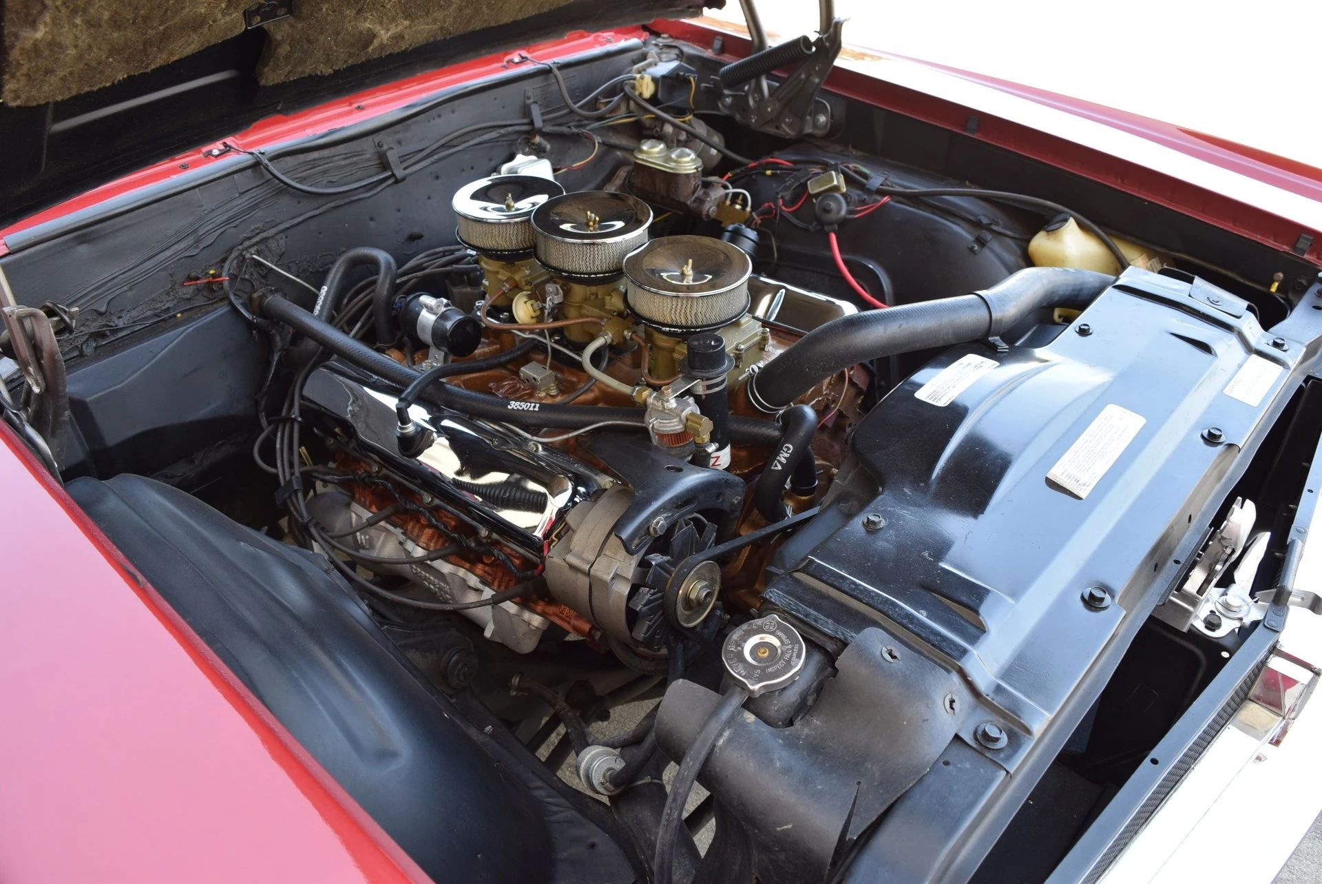Tri-Carb engine under the hood of a red 1966 Oldsmobile 4-4-2