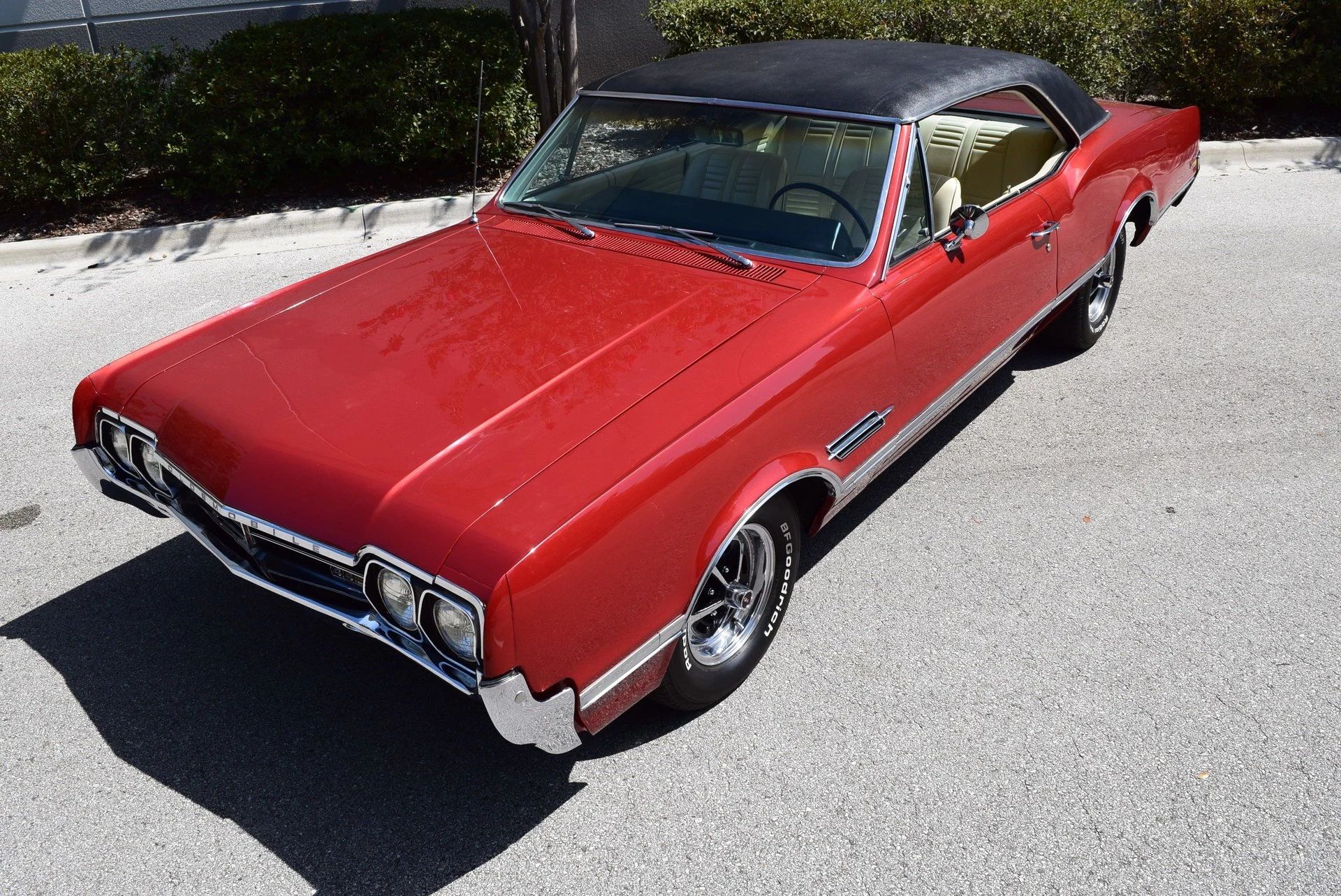 High angle front 3q view of a red 1966 Oldsmobile 4-4-2 hardtop with a black vinyl roof