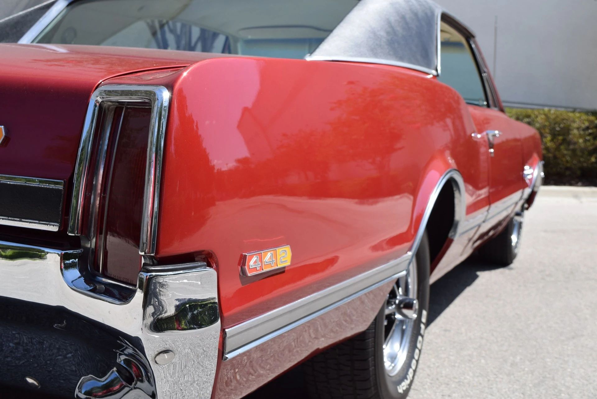 Right rear flank of a red 1966 Oldsmobile 4-4-2 hardtop with a black vinyl roof