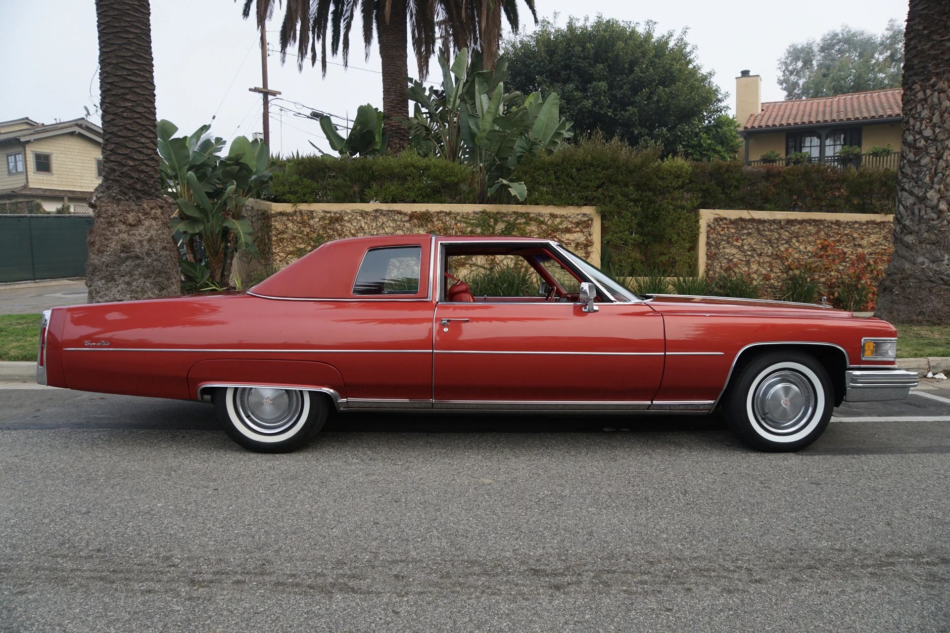 Color-Coordinated Cadillacs: Colorful Eldorados, De Villes, And Fleetwood Broughams 2 Right side view of a red 1975 Cadillac Coupe de Ville with a matching vinyl top