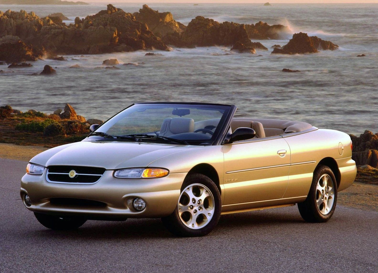 1994–1995 Chrysler LeBaron GTC Convertible – A Rental Car Favorite Nears Its Final Curtain 15 Press photo of a 1996 Chrysler Sebring convertible with its top down, photographed near a sea coast near sunset