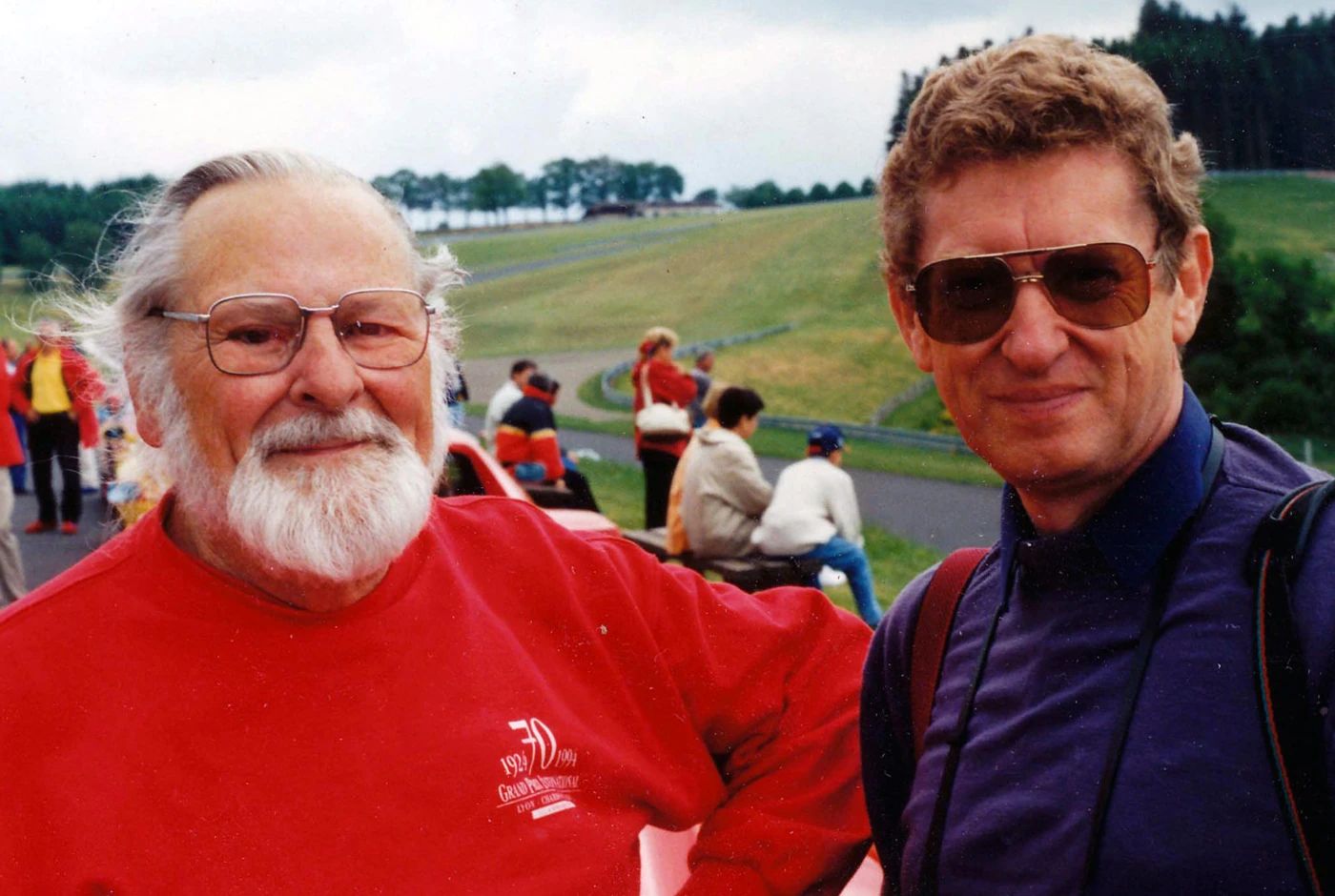 No, The Lincoln Continental Did Not Invent The Continental Kit: Griff Borgeson Makes The Case 2 Photo of Griffith Borgeson, a white man with glasses and a white beard, dressed in a red jumper, standing with a younger man in a blue jacket and sunglasses