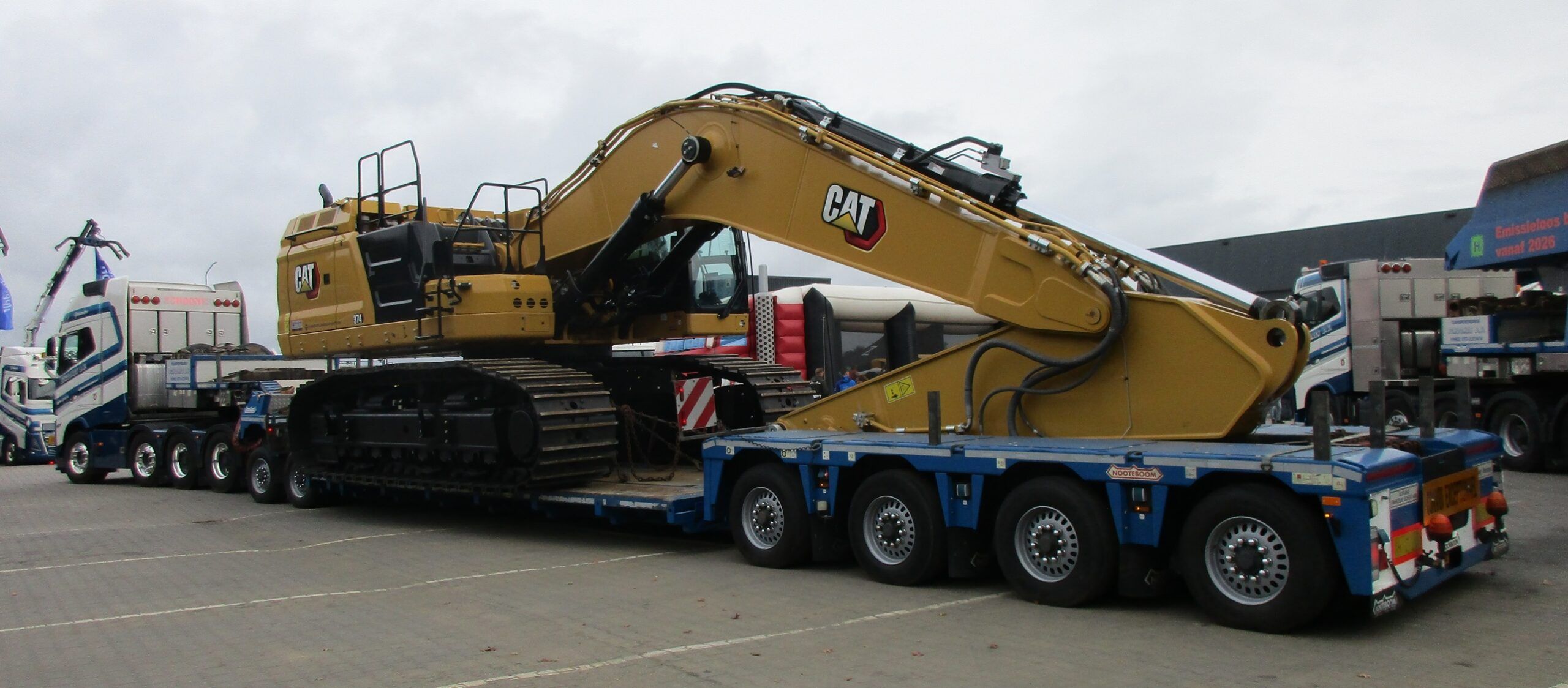 Photo of a giant yellow Caterpillar 374 tracked excavator, so big it's being carried on one trailer while its counterweight is carried on another