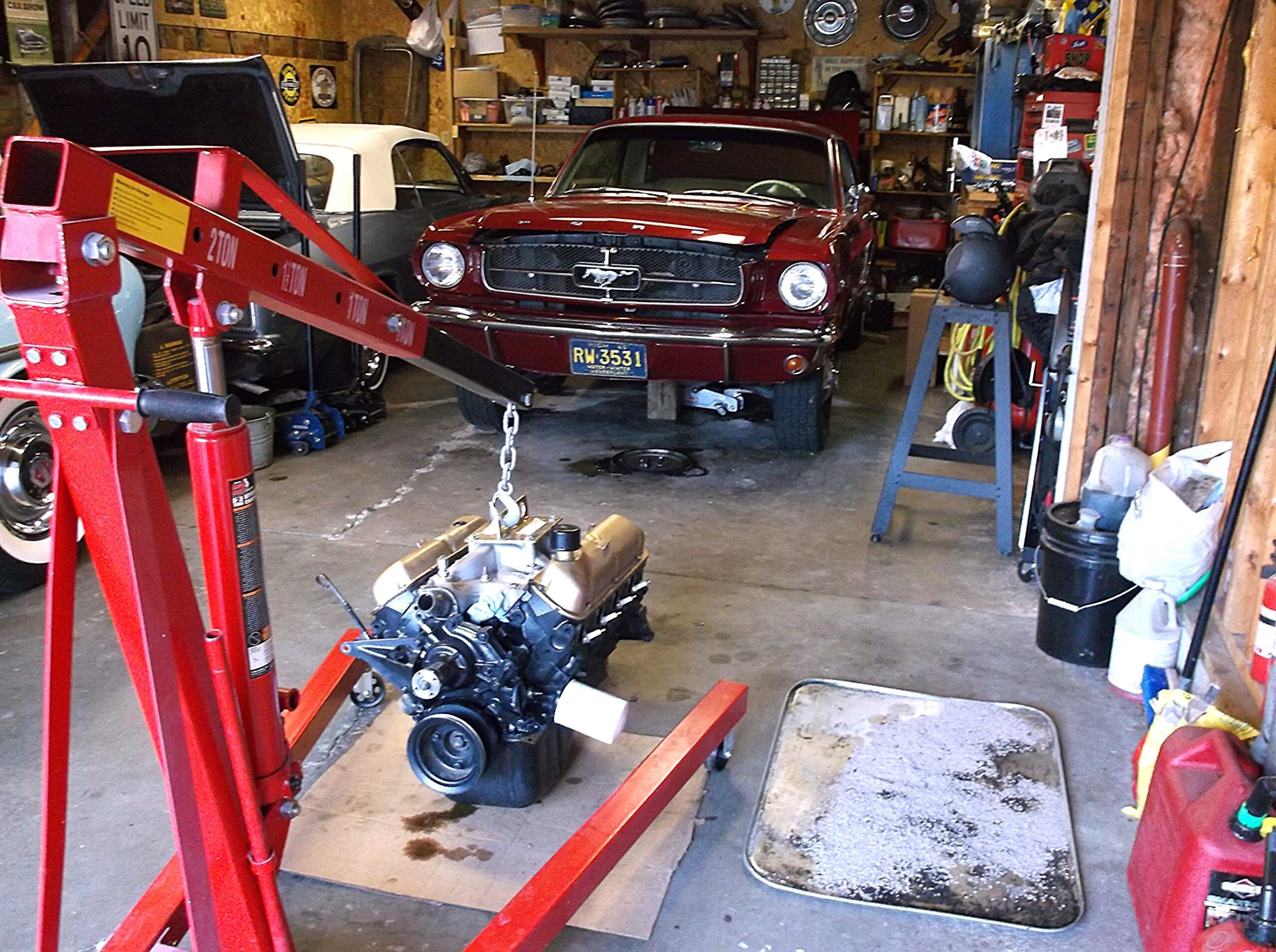Ford's Famous 289 V-8: Four Production Changes That Could Ruin Your Day 2 Picture of Ford 289 engine on an engine hoist in a garage in front of a 1965 Mustang coupe
