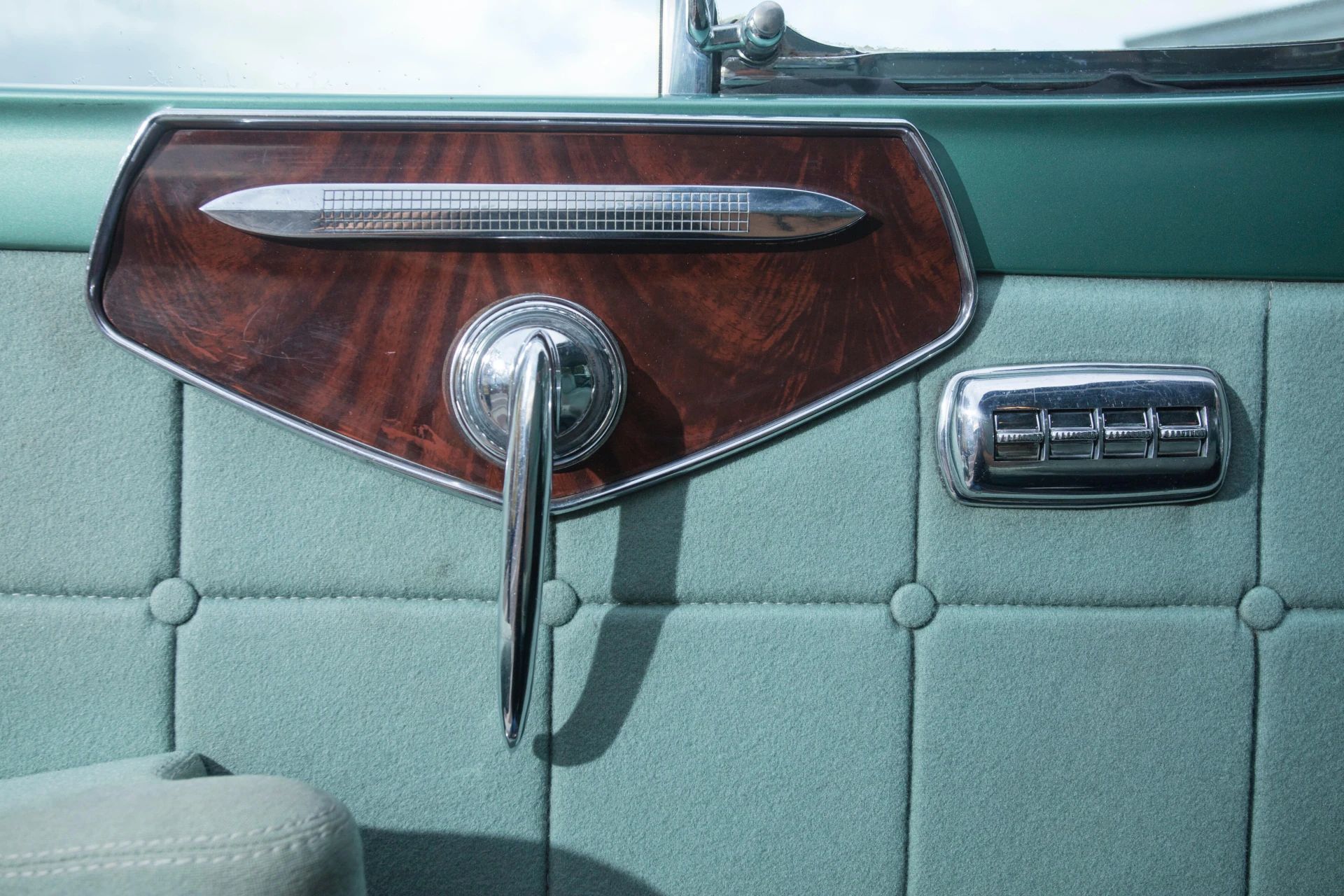 Driver's door pull and power window controls in a 1953 Chrysler C-58 Custom Imperial with green interior