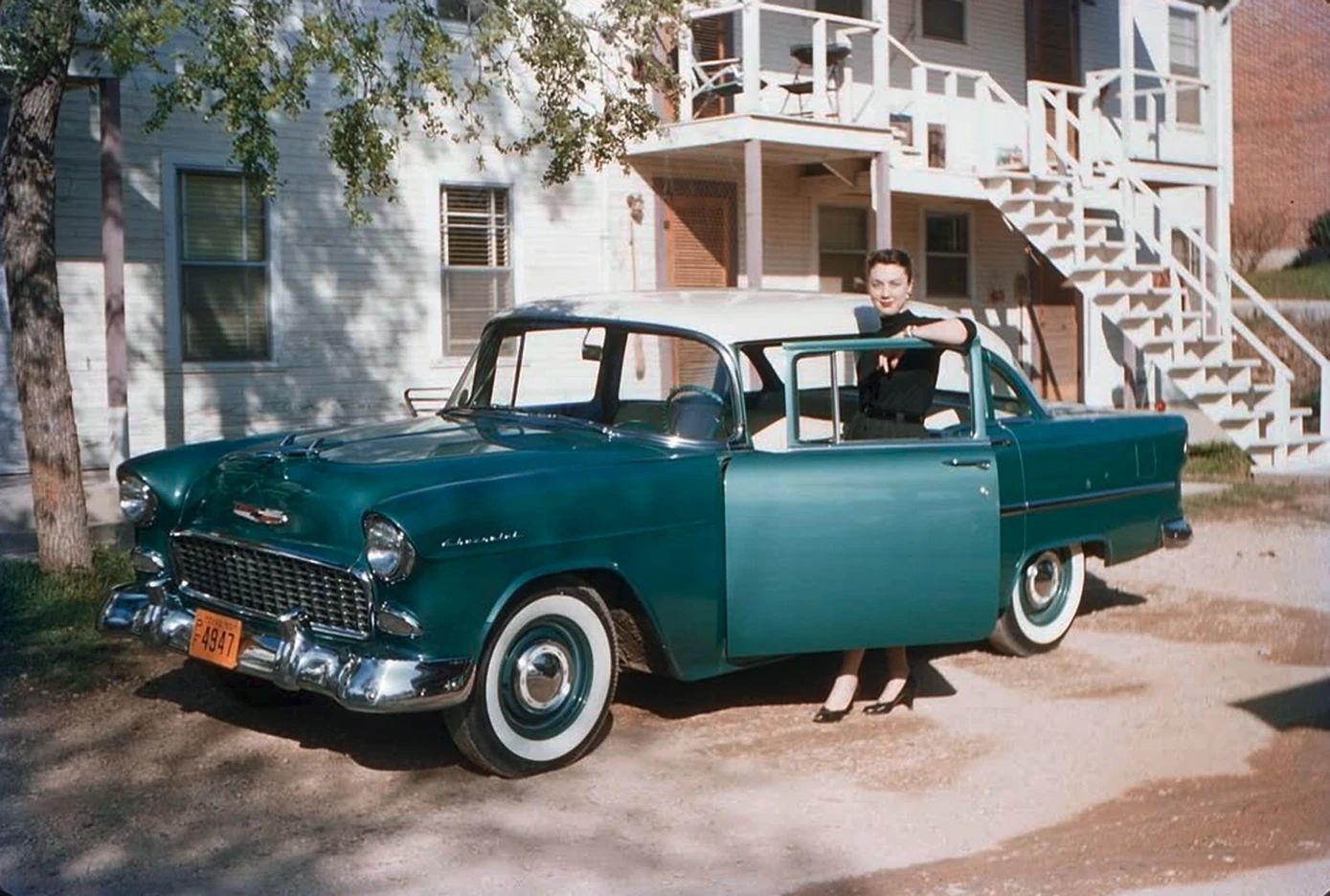 When Chrome Ruled: Classic 1950s GM Cars In Vintage Photos 1 Vintage photo of a well-dressed woman leading on the open door of a two-tone 1955 Chevrolet