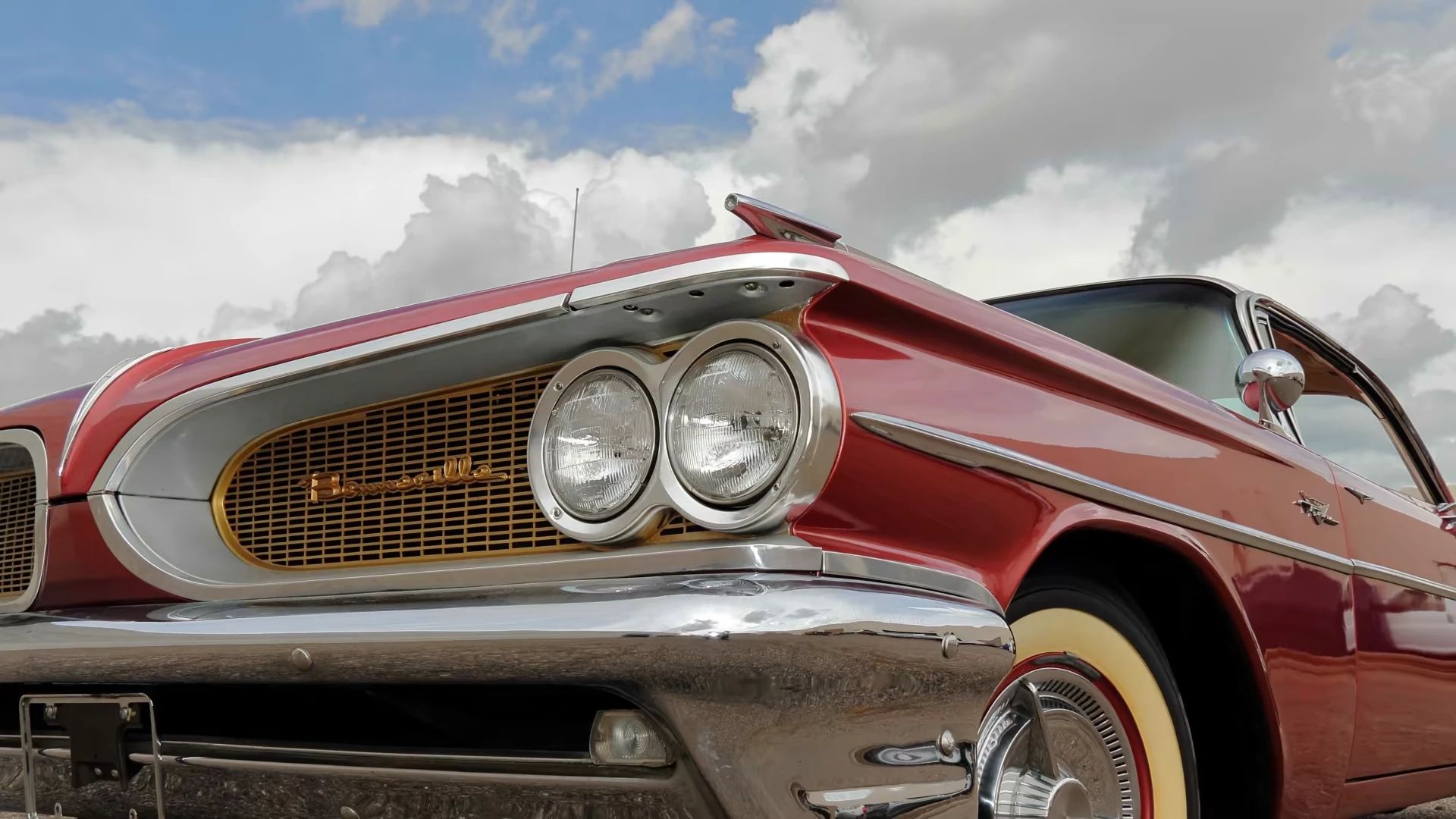 Low-angle closeup of the left headlights and fender of a red 1959 Pontiac Bonneville