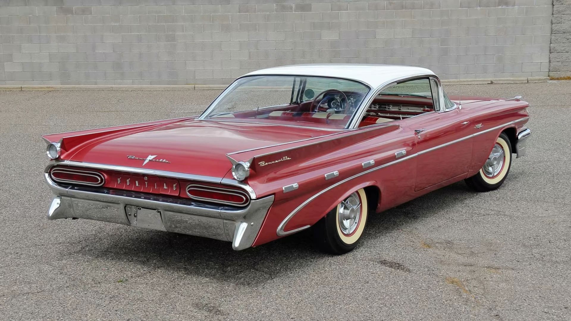 High-angle rear 3q view of a red 1959 Pontiac Bonneville two-door hardtop with a white roof