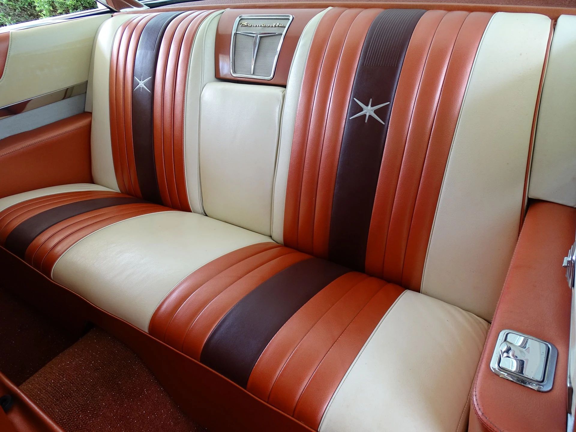 Back seat of a 1959 Pontiac Bonneville two-door hardtop with tri-tone white, red, and brown upholstery, seen through the driver's door