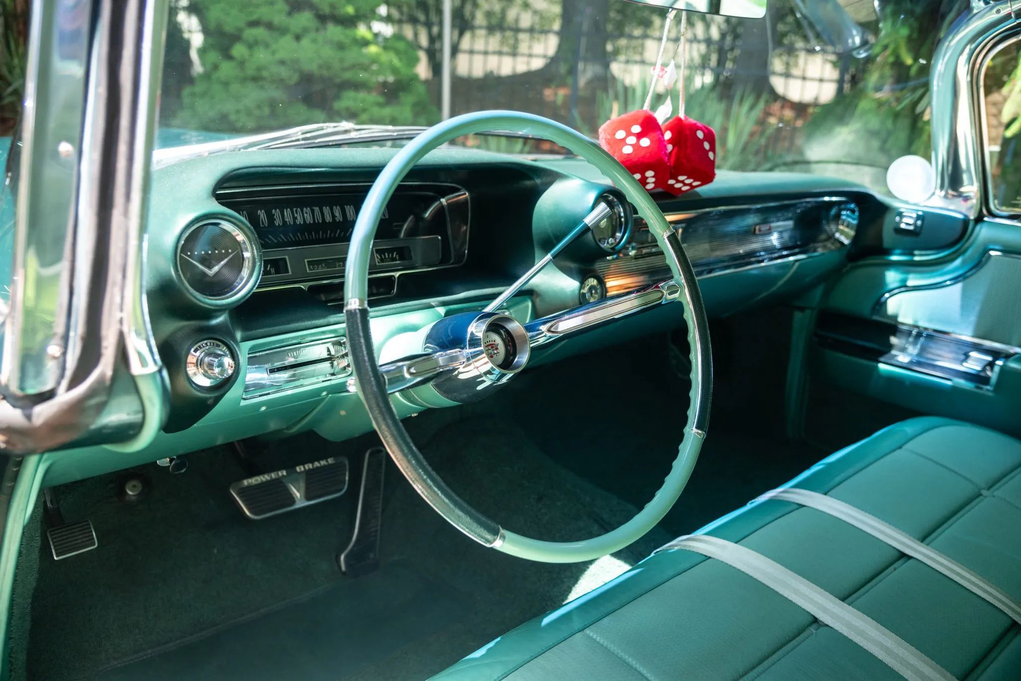 1960 Cadillac Fleetwood Sixty Special: Enviably Green, But No A/C 19 Dashboard of a 1960 Cadillac Fleetwood with green interior and a light green steering wheel with darker green grips; there's a pair of fuzzy dice hanging from the rear-view mirror