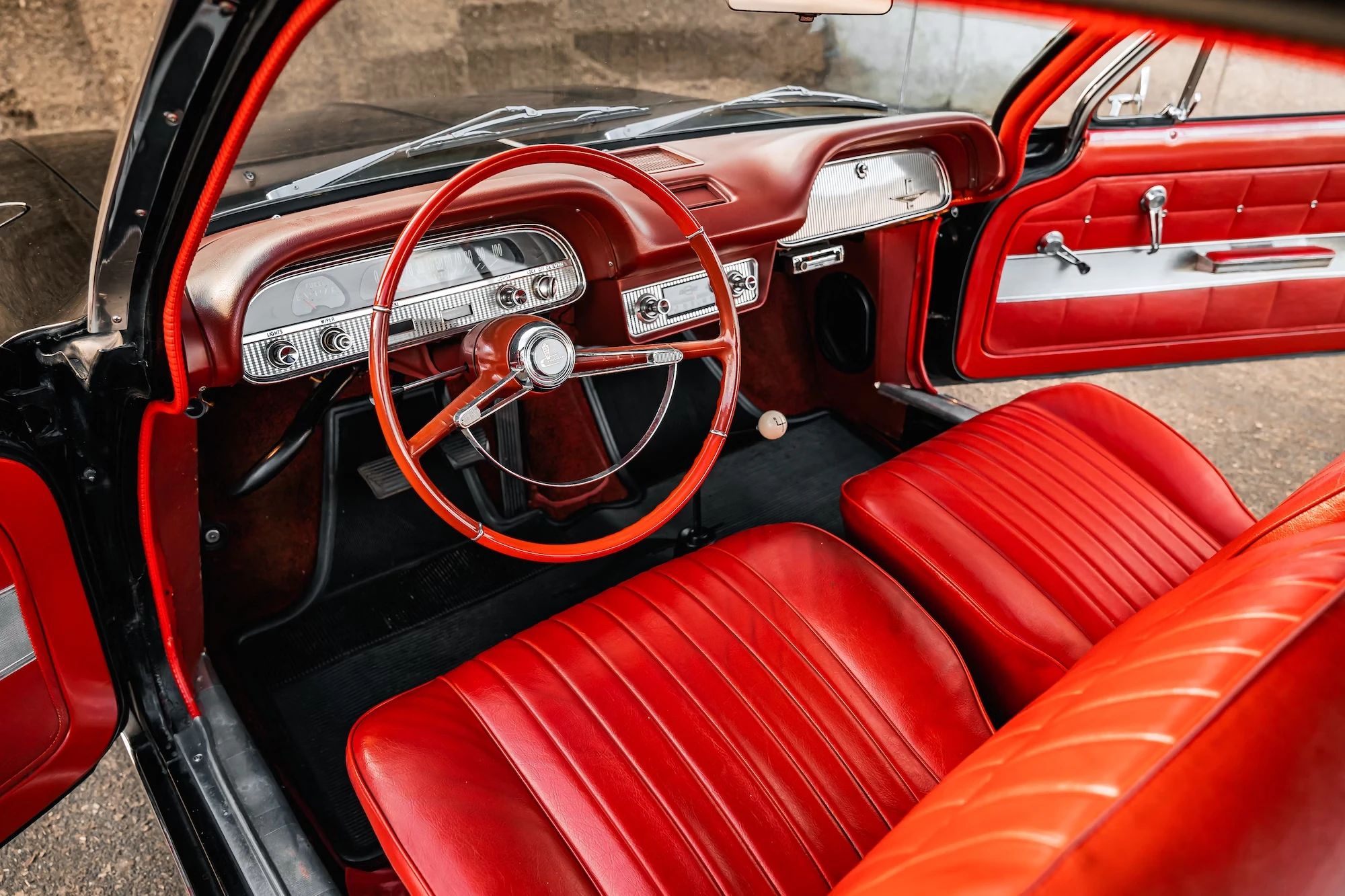 Front seats of a 1962 Chevrolet Corvair coupe with a red interior and 4-speed