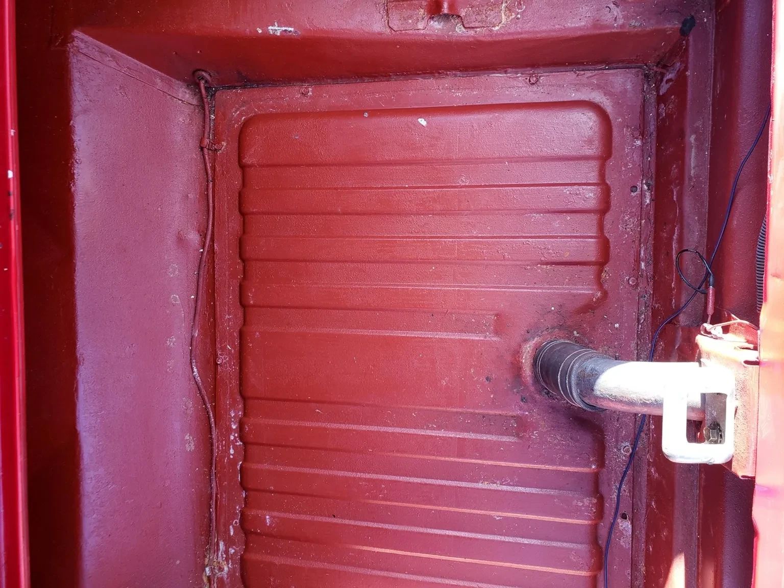 Photo of the gas tank and fuel filler in the trunk of a red 1965 Ford Mustang hardtop