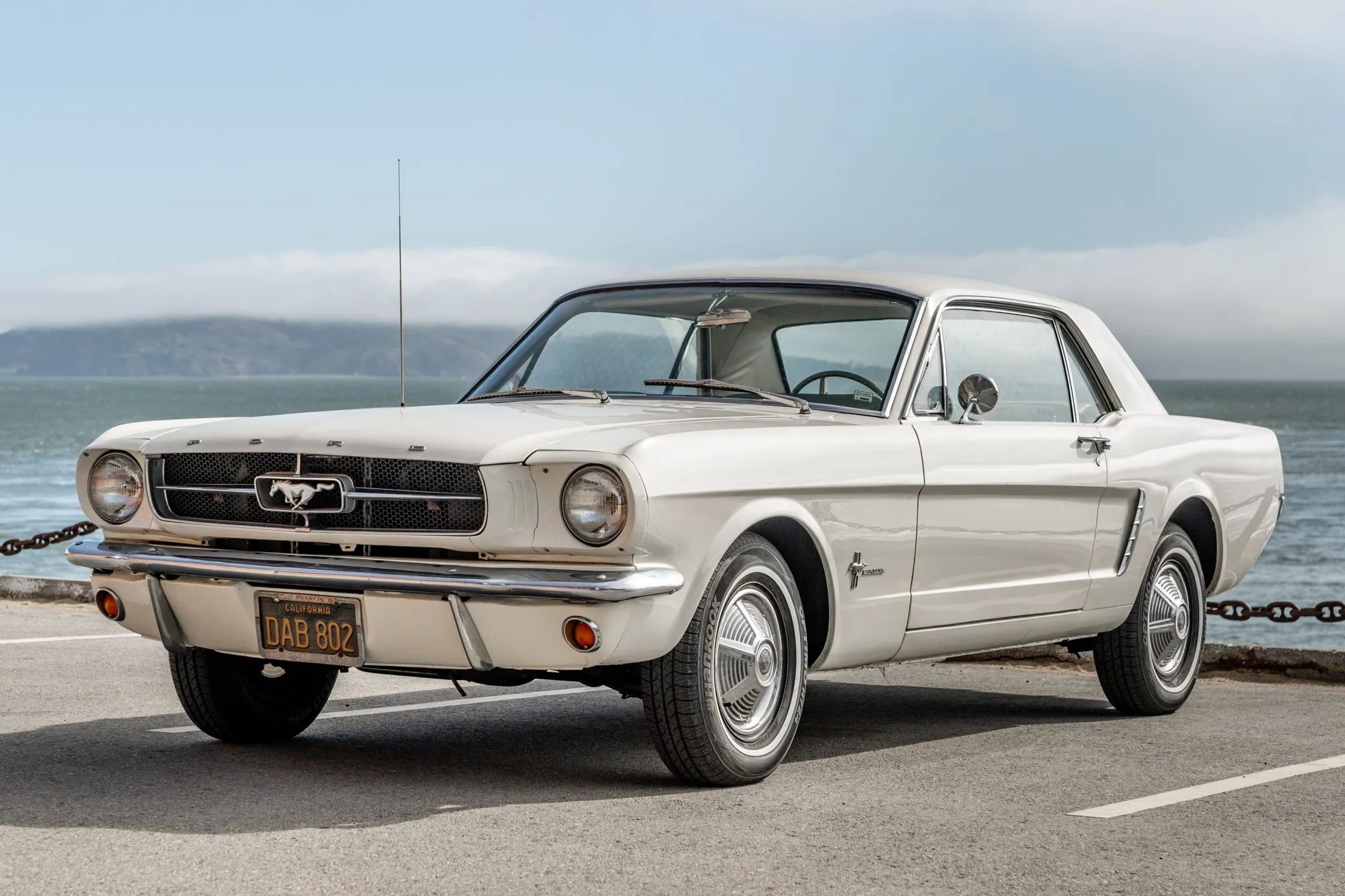 CC Tech: How the Mustang, Cougar, And Maverick Differed From The Original Ford Falcon Platform 20 Left front 3q view of a white 1965 Ford Mustang hardtop in a coastal setting