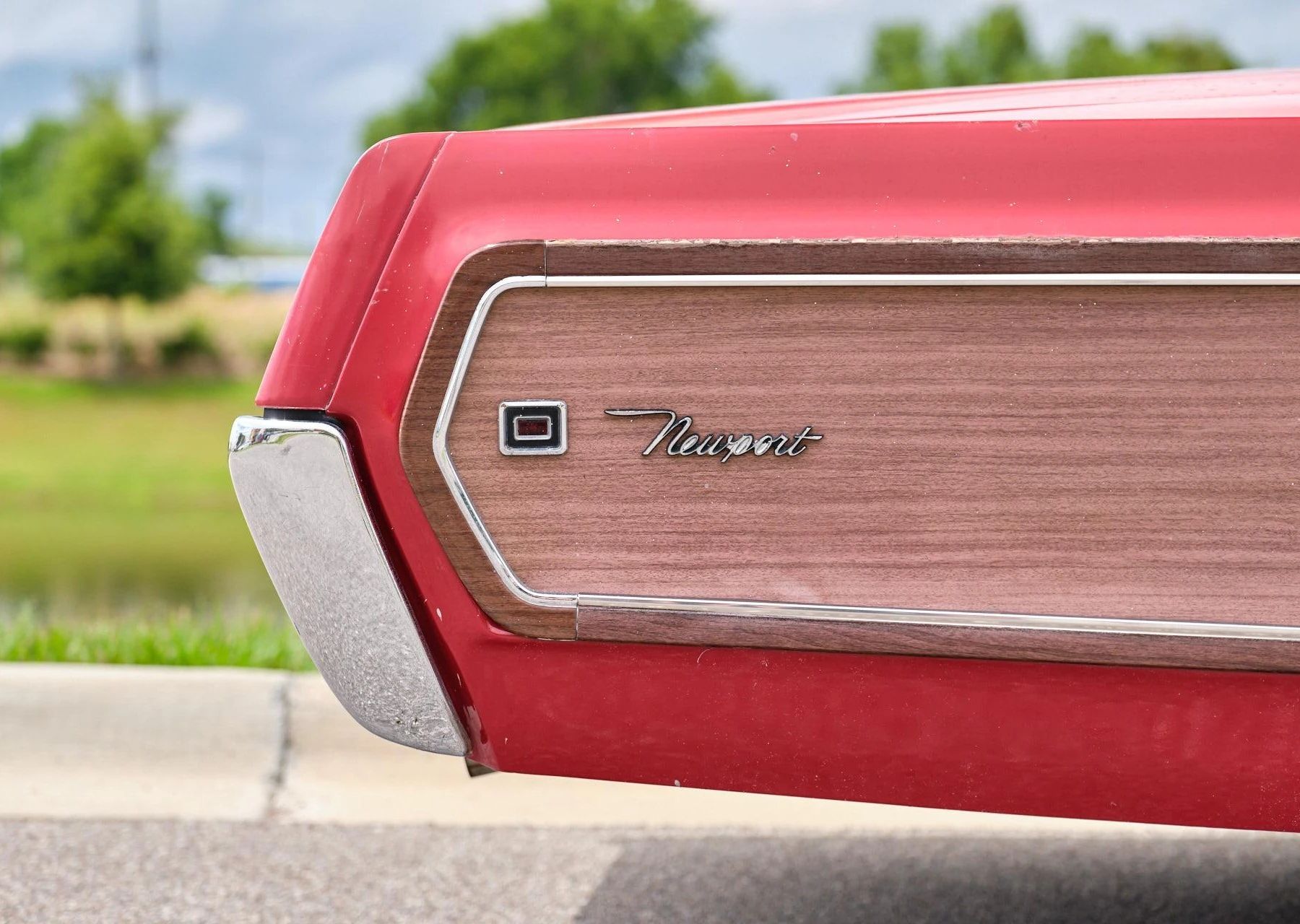 Tail of a red 1968 Chrysler Newport, showing the rear fender badge and woodgrain side trim