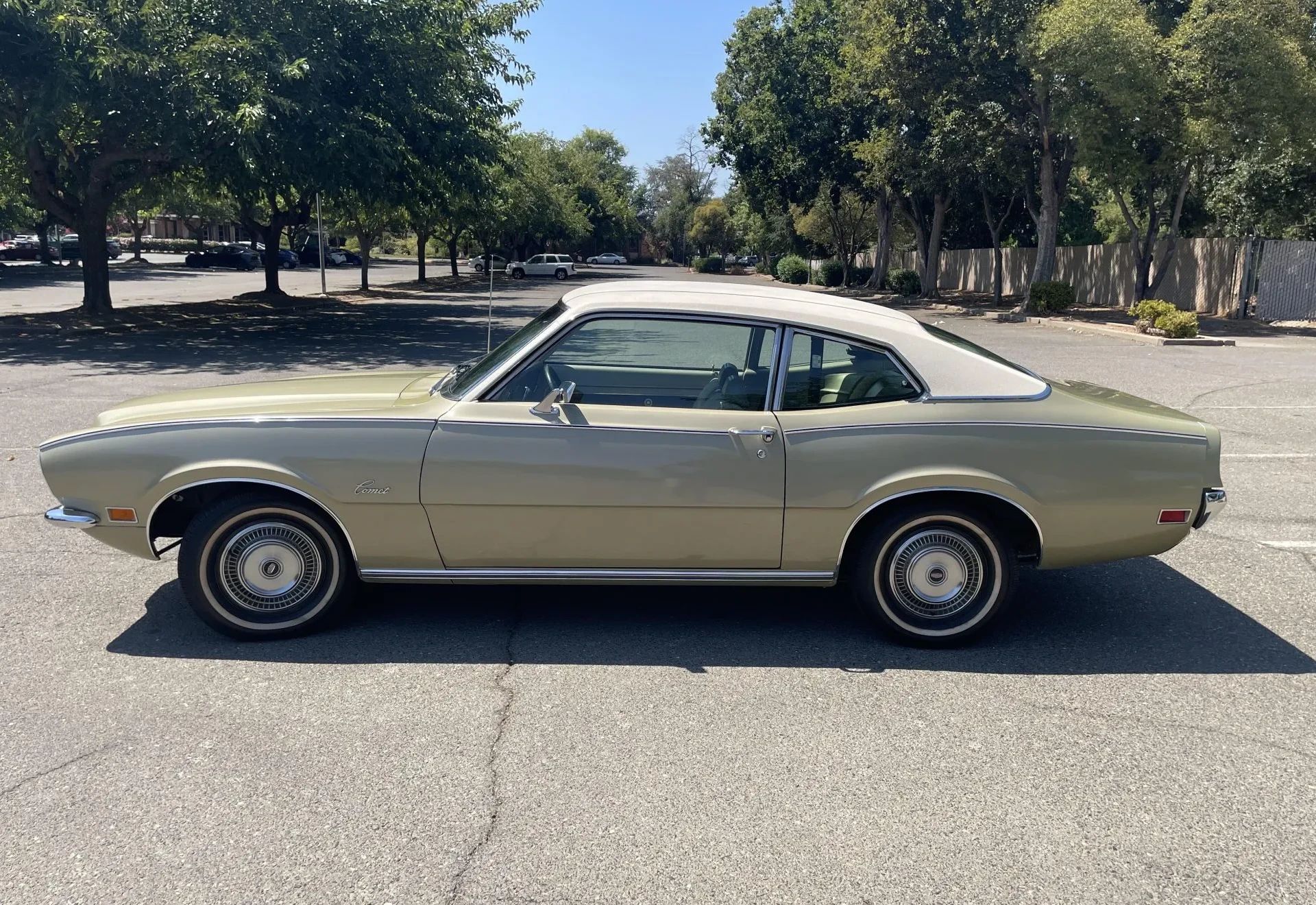 Left side view of a gold 1971 Mercury Comet two-door sedan with a beige vinyl roof