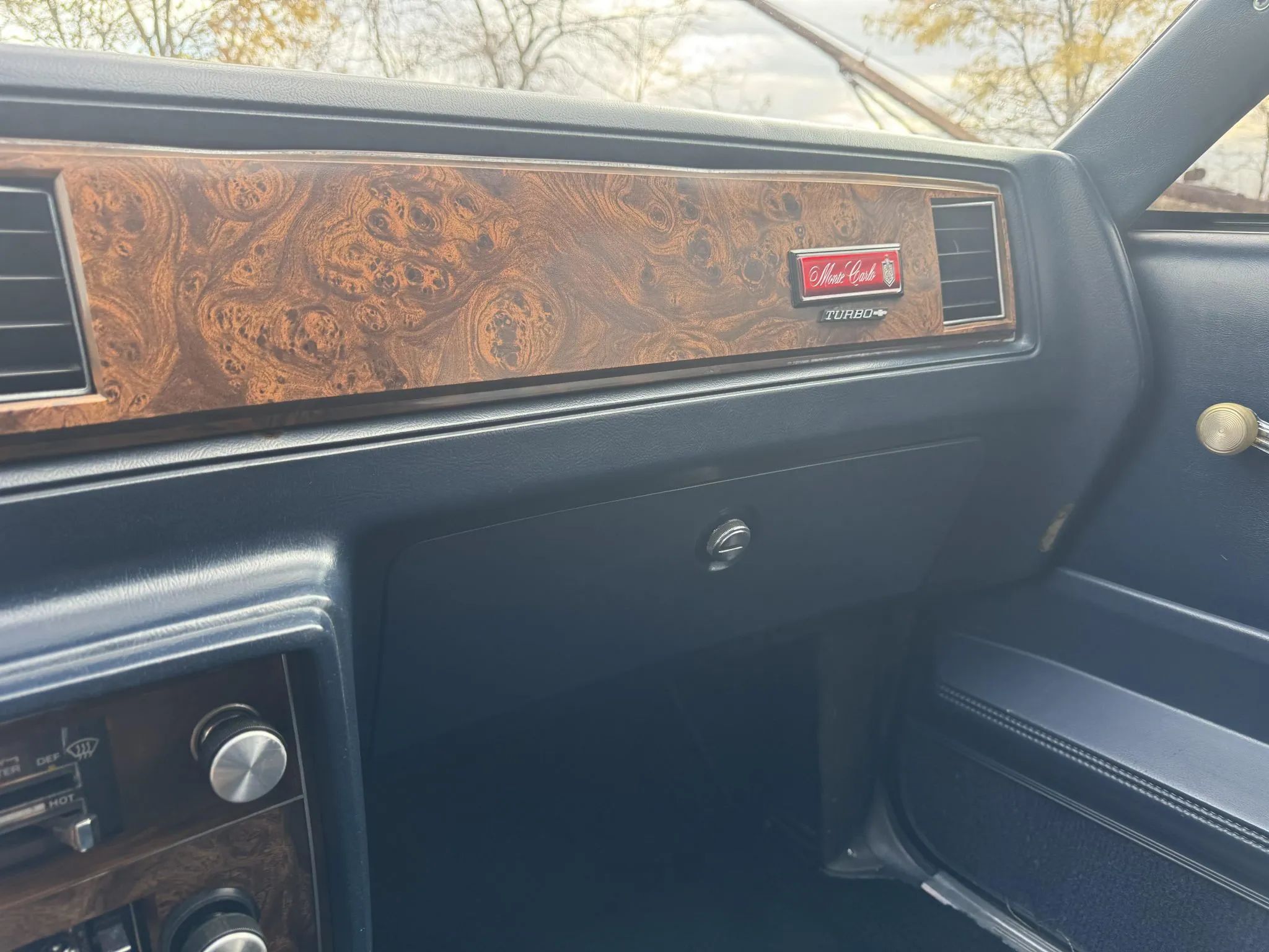 Rare Survivor: 1981 Chevrolet Monte Carlo Turbo V6 – Forgotten Chevy Still In Great Shape 11 Right side of the dash of a 1981 Chevrolet Monte Carlo with a blue interior. It has a "Turbo" badge under the Monte Carlo emblem.