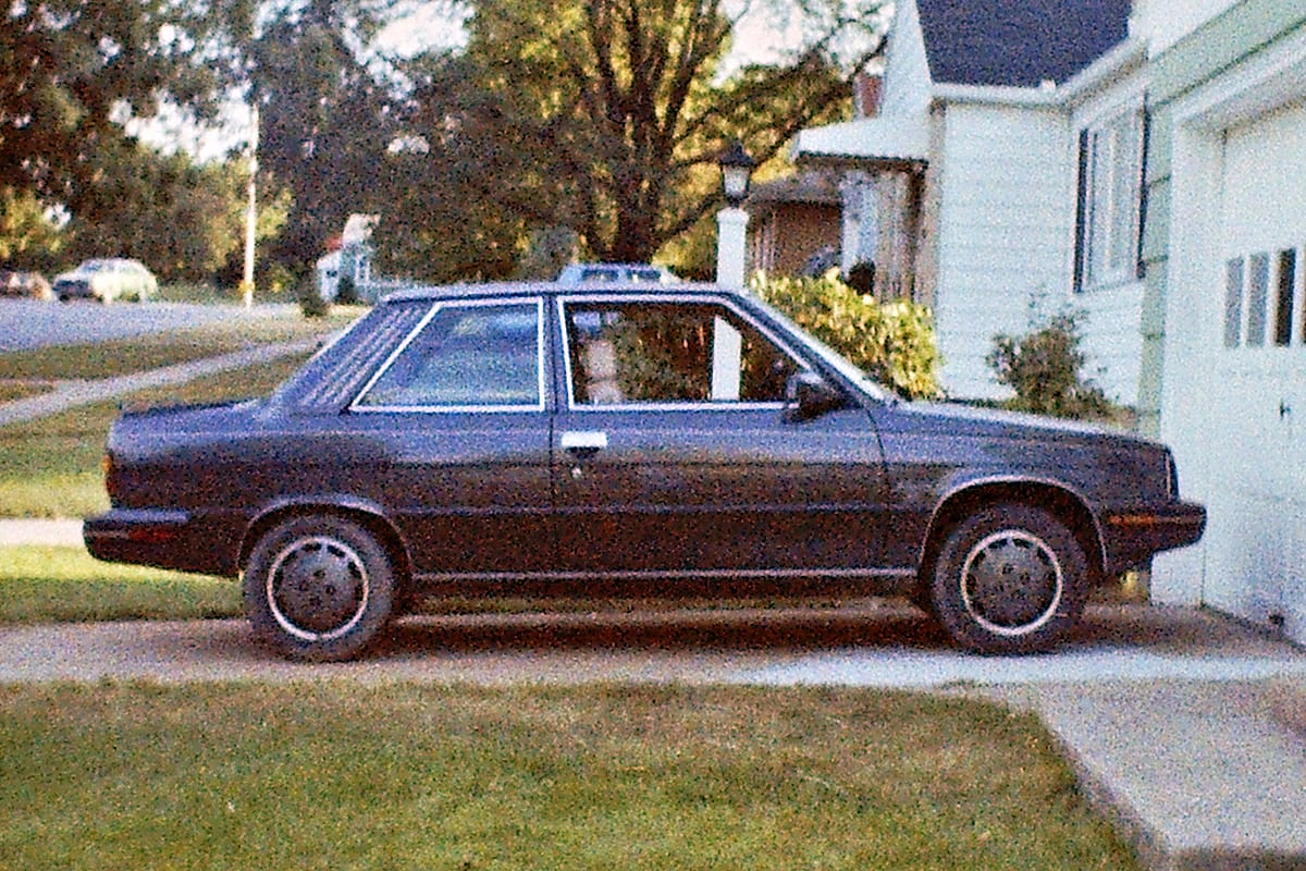 Old color photo of a black 1983 Renault Alliance in a driveway