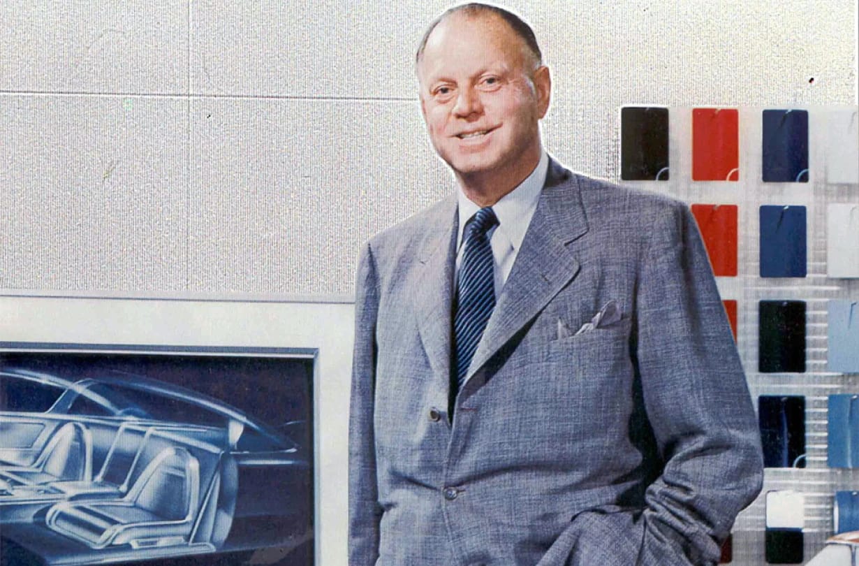 Color photo of Harley Earl in a styling studio, wearing a blue suit
