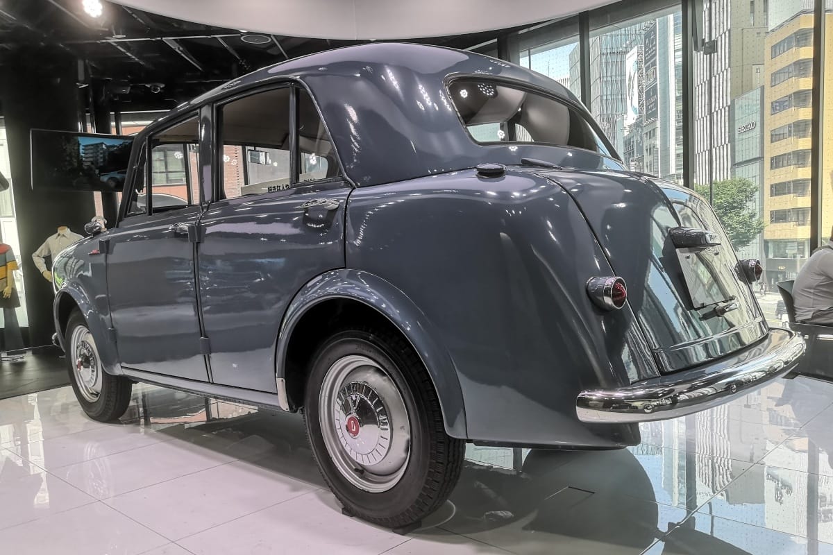 Museum Classic: 1956 Datsun 113 Sedan – A Giant Awakes 1 Rear view of a gray 1956 Datsun 113 four-door sedan in a museum display