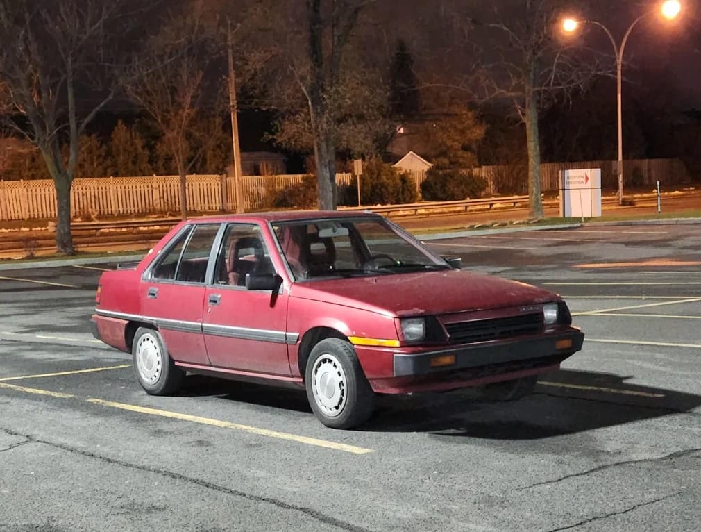 My 1986 Dodge Colt: Angular Mid-'80s Moparbishi With 4 Doors For A Young Family 1 Photo of a red 1986 Dodge Colt sedan in a parking lot at night