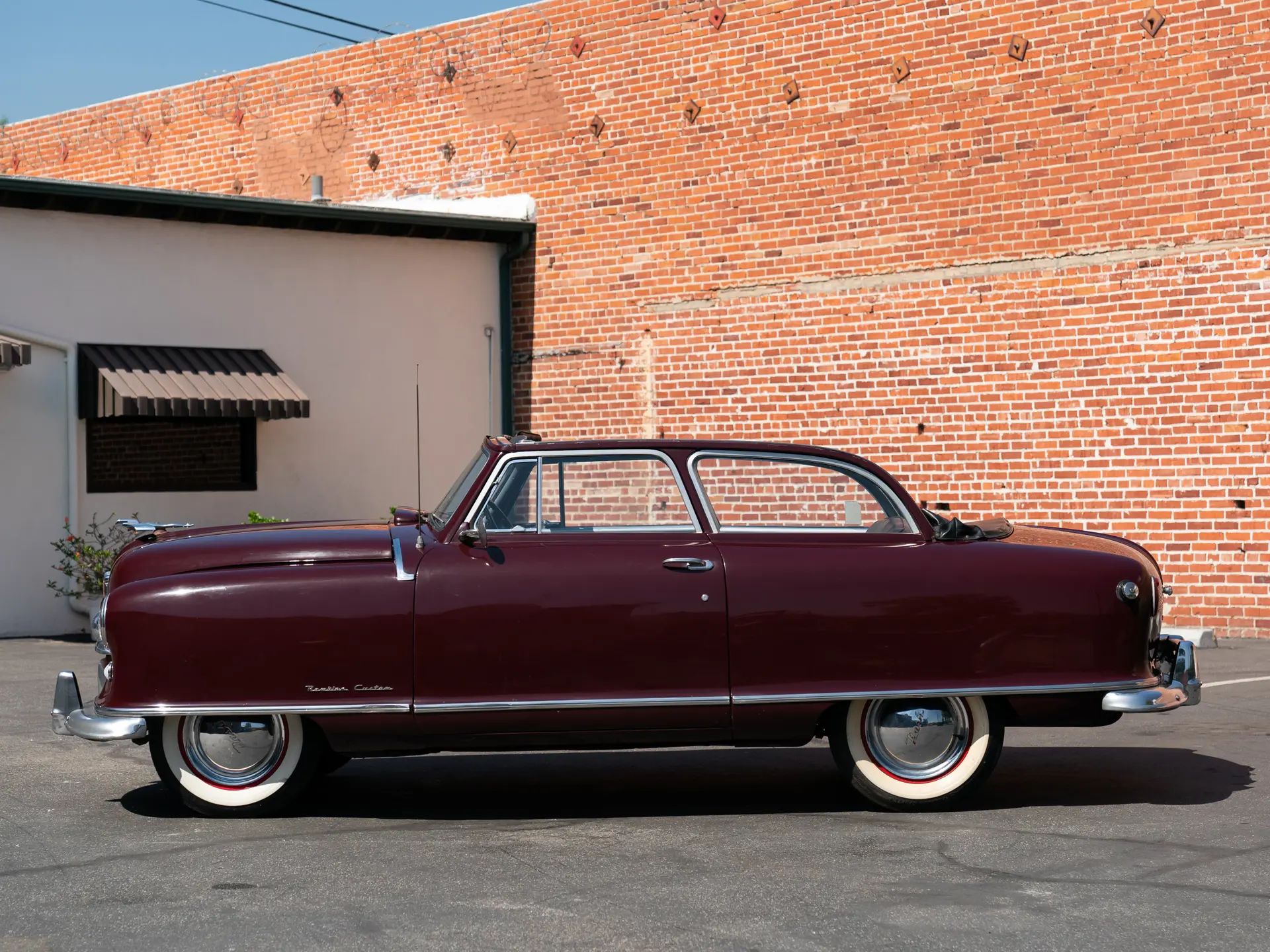 "Don't Try This With A Conventional Convertible" 5 Left side view of a maroon 1950 Nash Rambler Convertible Landau with its top down
