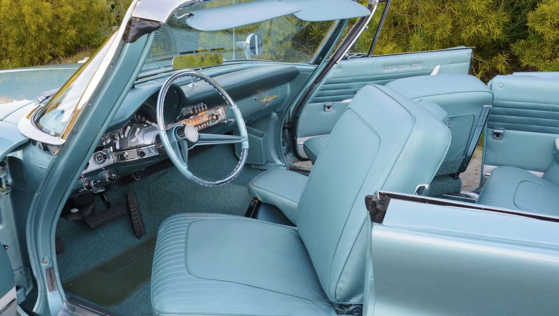 Driver's side swiveling bucket seats of a turquoise 1960 Chrysler Imperial convertible