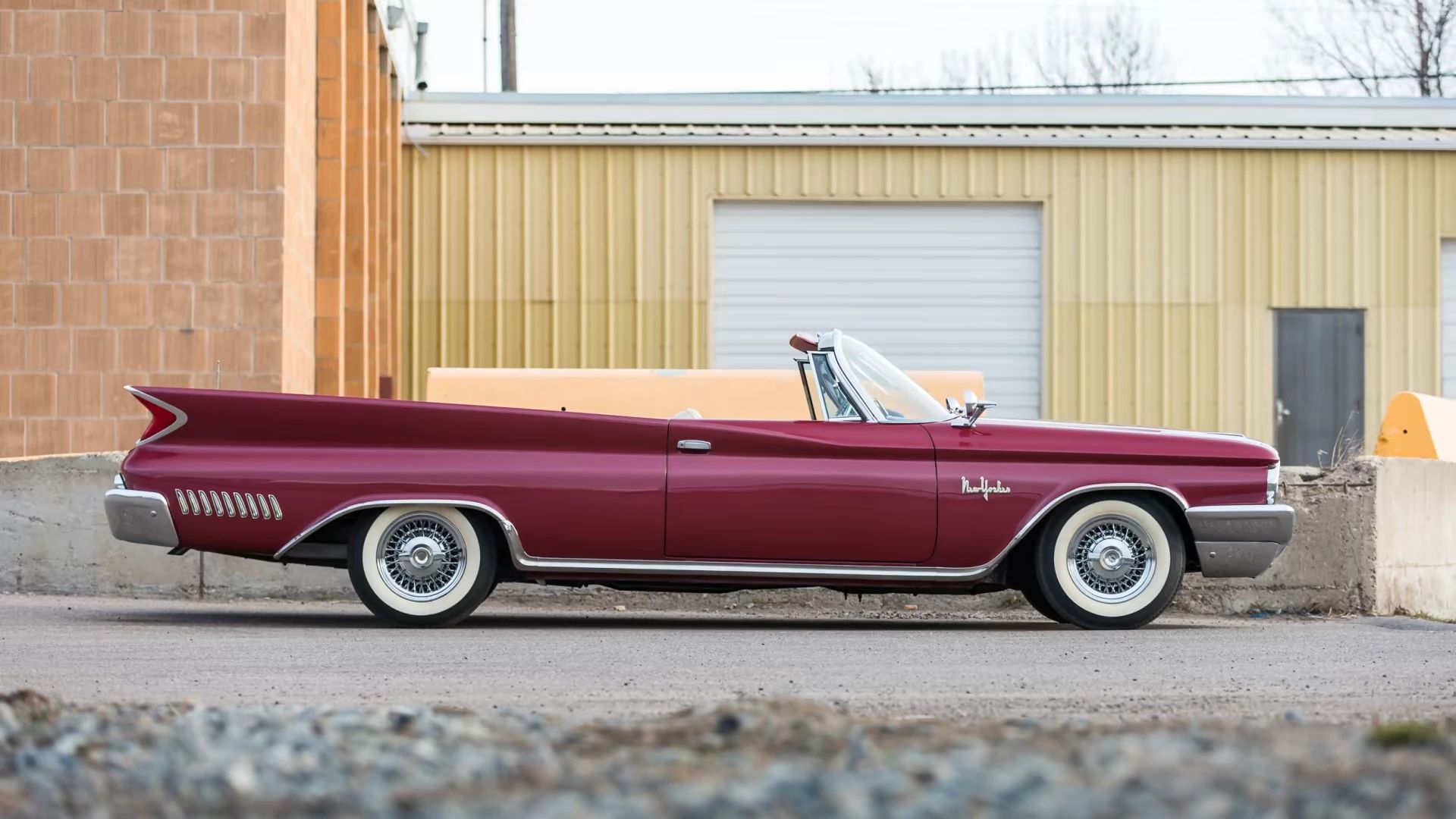 Right side view of a red 1960 Chrysler Imperial convertible with wire wheels