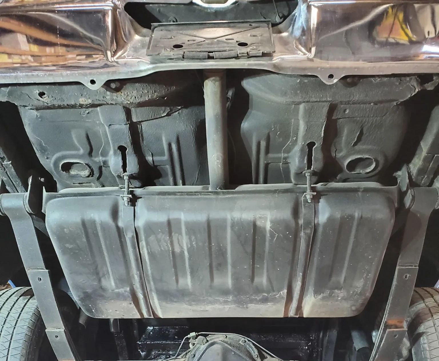 Fuel tank and fuel filler pipe of a 1968 Chevrolet Nova, seen from below with the car on a hoist
