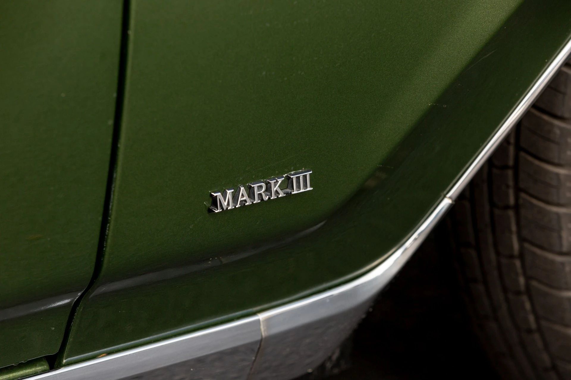 "Mark III" badge on the front fender of a dark green 1971 Lincoln