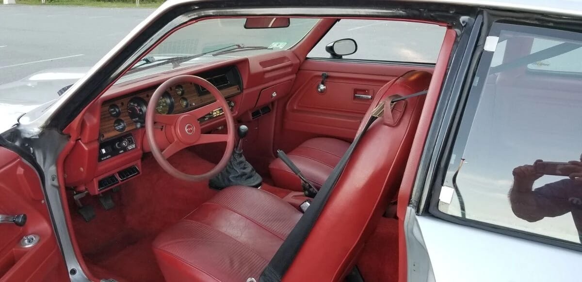 Front seats and dashboard of a 1977 Chevrolet Vega with a red interior