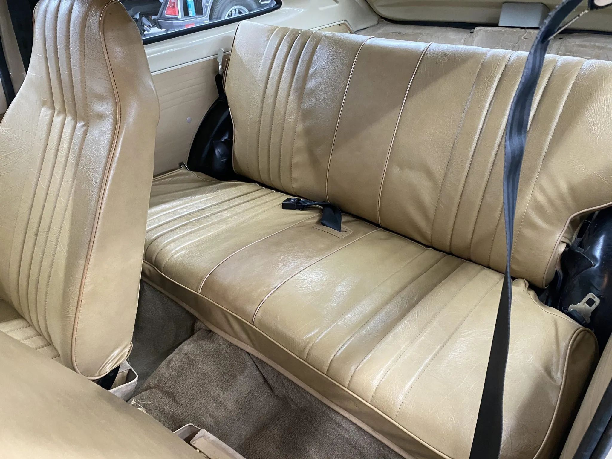 Back seat of a 1981 Chevrolet Chevette three-door with beige vinyl upholstery