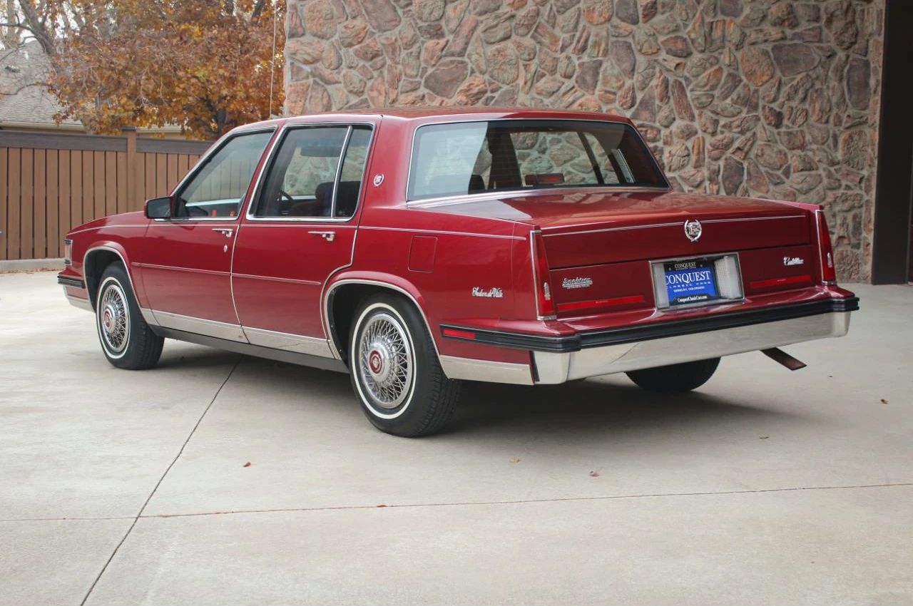 Left rear 3q view of a red 1985 Cadillac Sedan de Ville four-door sedan