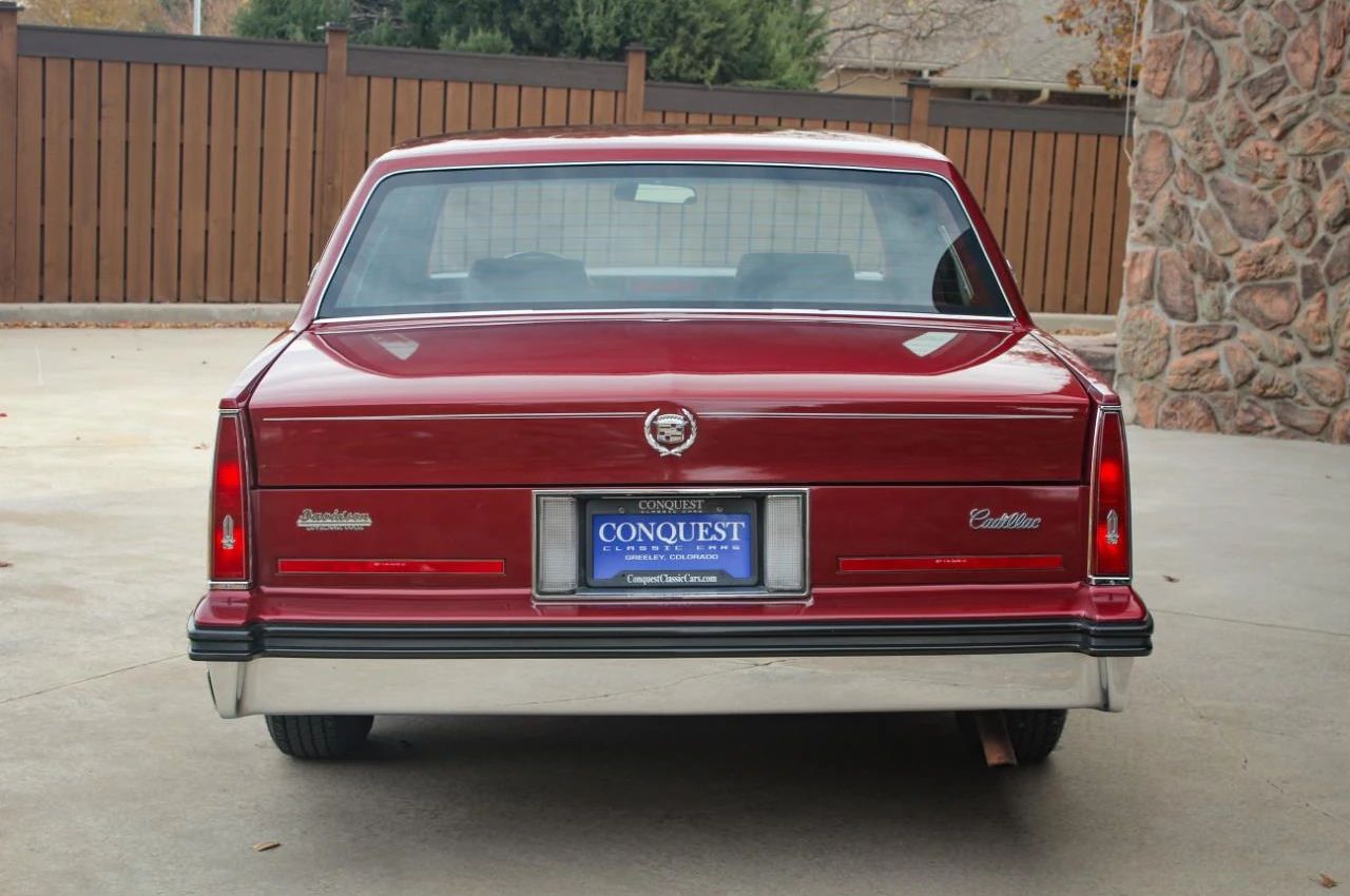 Rear view of a red 1985 Cadillac Sedan de Ville four-door sedan