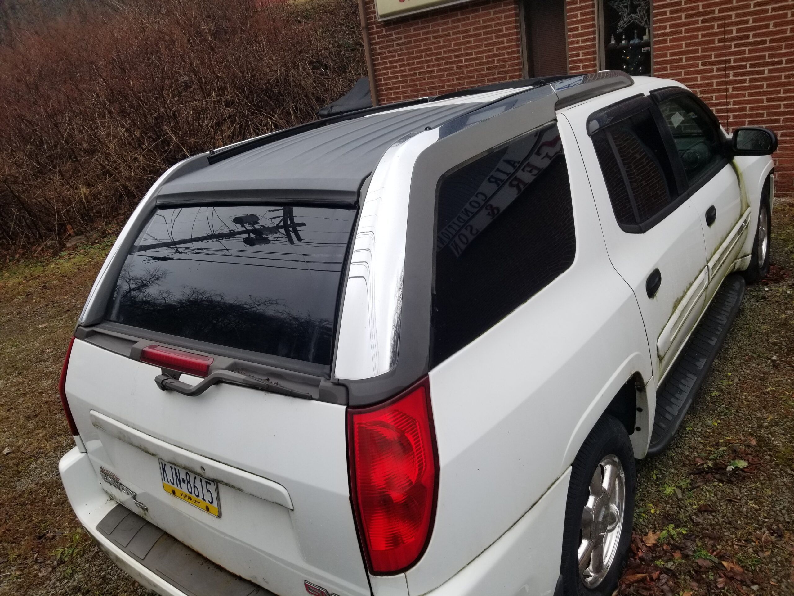Rear view of a white 2004 GMC Envoy showing its retractable roof