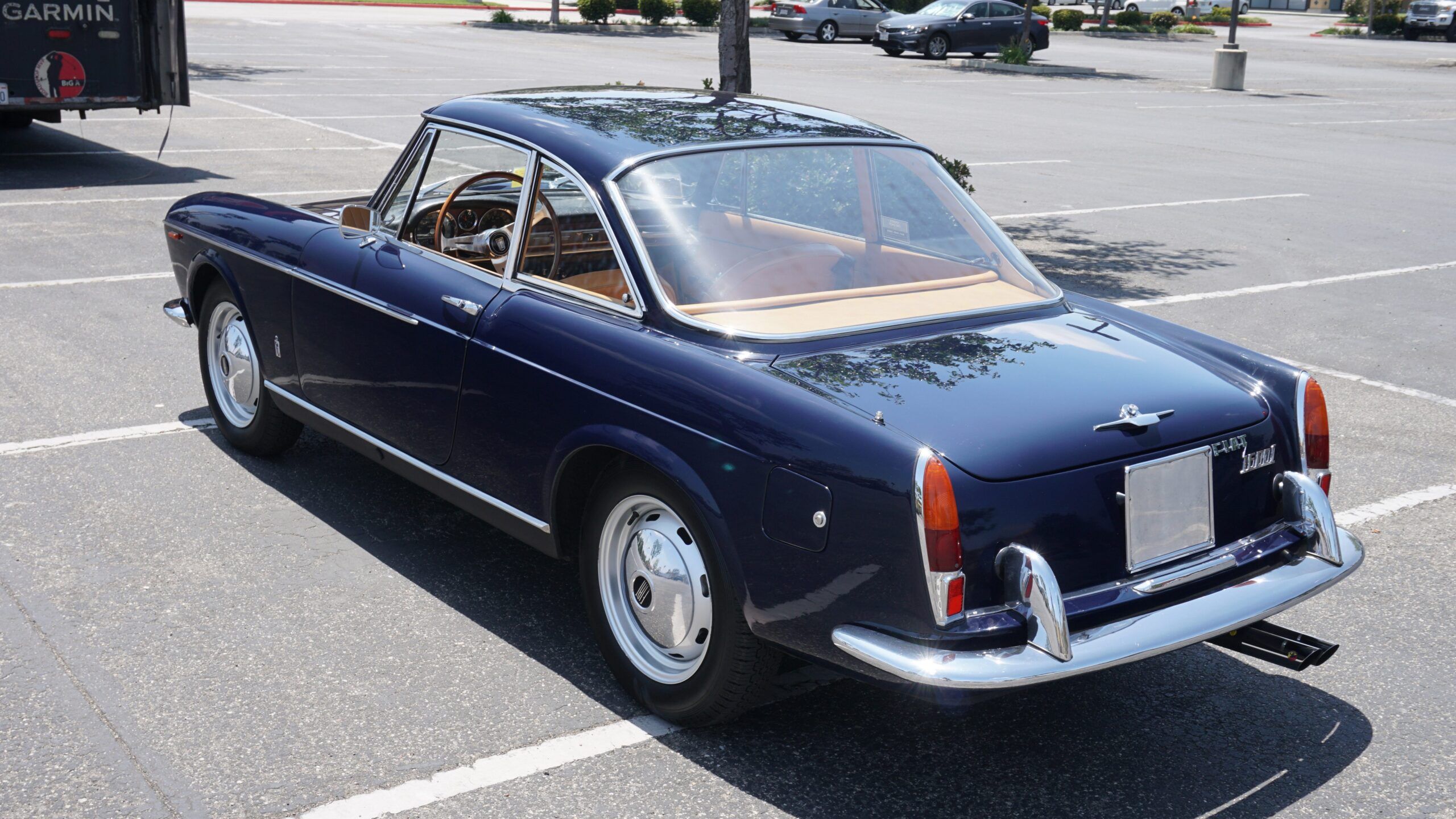 Pininfarina's Shared Language of Beauty in 1963—From Ferrari to FIAT 9 Image of dark blue FIAT 1600S Coupe in a parking lot waiting to get loaded onto a delivery truck