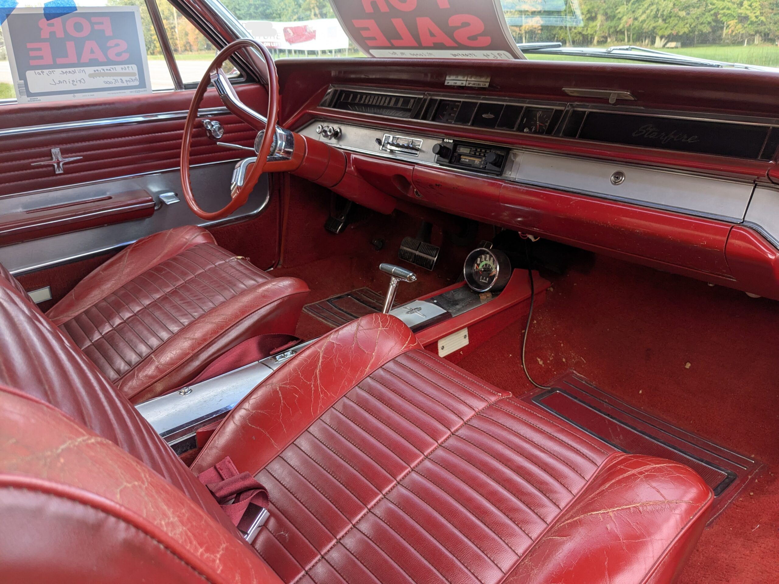 Image of 1964 Oldsmobile Starfire interior in red with bucket seats and a console