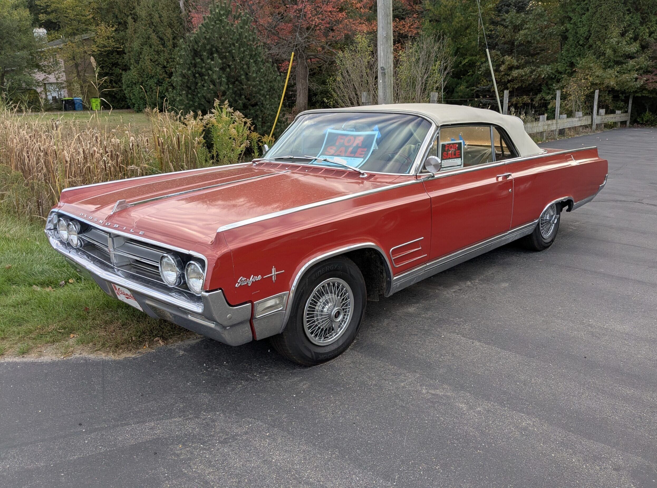 1964 Oldsmobile Starfire Convertible parked on the road with a FOR SALE sign.